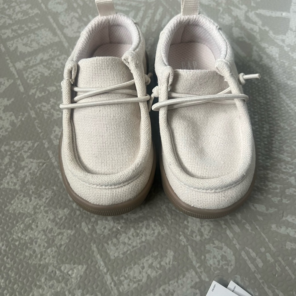 A lot of two baby shoes, size 5 cream colored gap shoes, and blue hey dudes.